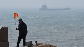 Un homme marche avec derrière lui un bateau sur l'île de Pingtan, le point le plus proche entre la Chine et Taïwan.