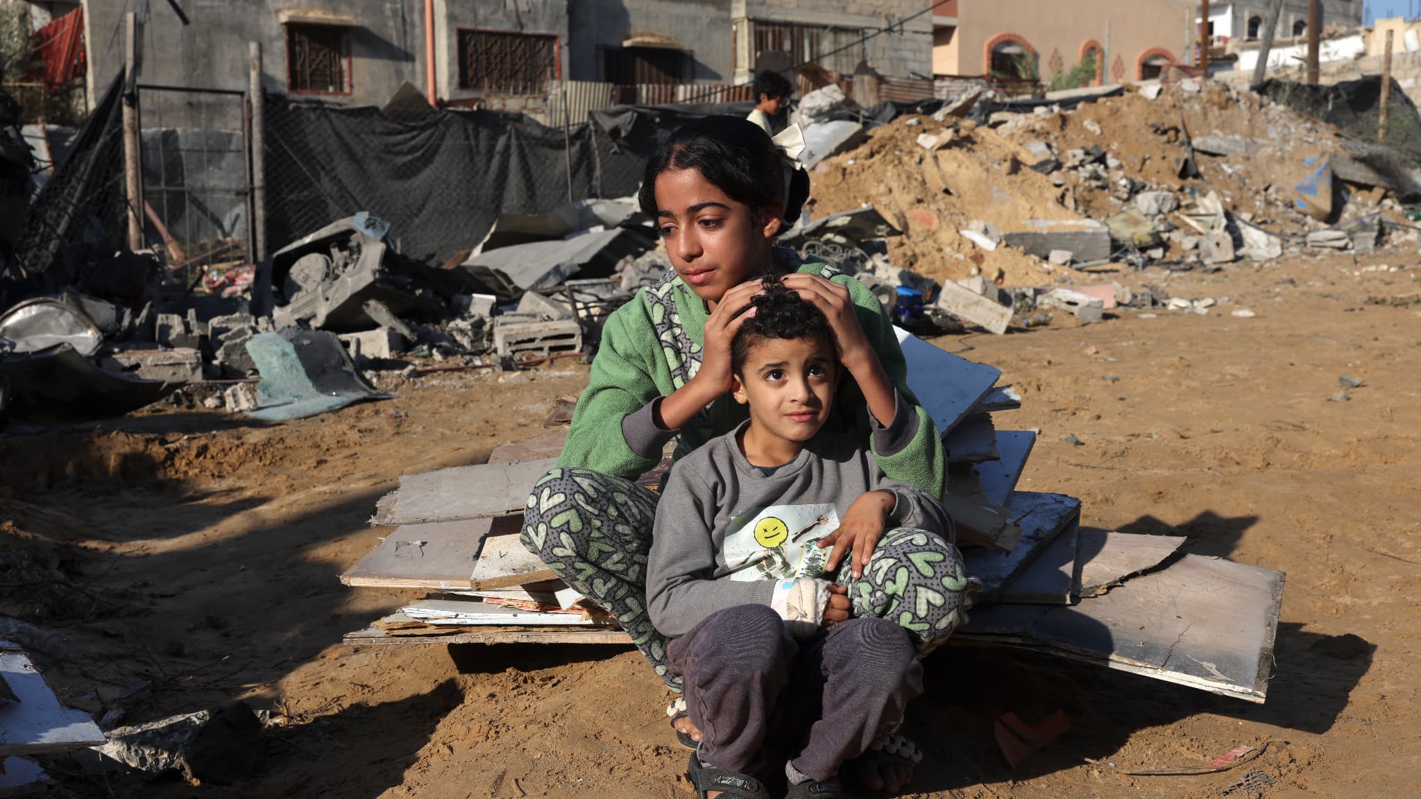 Une fillette palestinienne et son frère sont assis au milieu des débris d'une maison après une frappe israélienne à Rafah, dans le sud de la bande de Gaza, le 18 novembre 2023,