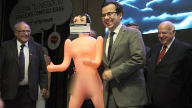 Sur la bouche de la poupée gonflable offerte au ministre on peut lire "Pour stimuler l'économie"