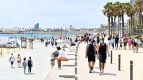 Les gens marchent sur la promenade de la plage de Bogatell le 6 juin 2021 à Barcelone. L'Espagne autorisera tous les voyageurs vaccinés à visiter le pays à partir du 7 juin, car le point chaud du tourisme vise à relancer son industrie du voyage battue par les virus. 