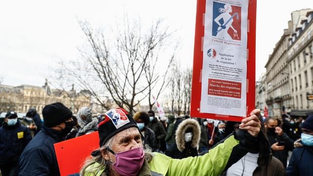 Un homme tient une pancarte pendant la manifestation organisée par l'association Droit au logement, ce samedi 2 janvier à Paris.