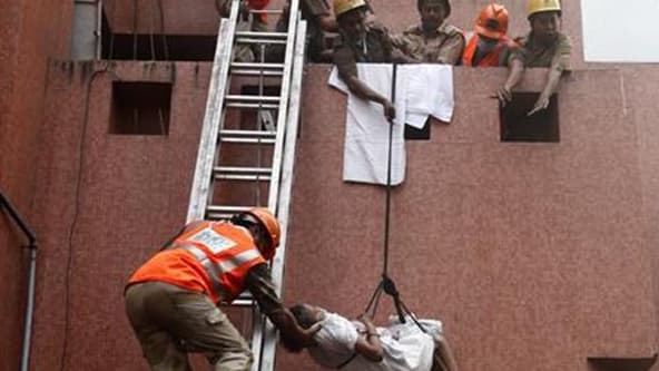 Evacuation d'un patient par des pompiers dans un hôpital de Calcutta, dans l'est de l'Inde. Un incendie a ravagé vendredi cet établissement de sept étages, faisant au moins 84 morts, en majorité des patients qui dormaient lorsque le sinistre s'est déclaré
