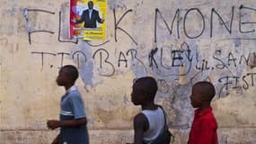 Enfants devant une Affiche électorale en faveur d'Alpha Condé à Conakry. Les autorités guinéennes ont décidé de reporter le second tour de l'élection présidentielle prévu dimanche en raison de préparatifs insuffisants, ont indiqué mercredi des responsable