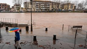 Un piéton muni d'un parapluie marche dans les rues inondées d'Agde, dans le sud de la France, après que l'Hérault est sorti de son lit à la suite de fortes pluies, le 23 décembre 2025.
