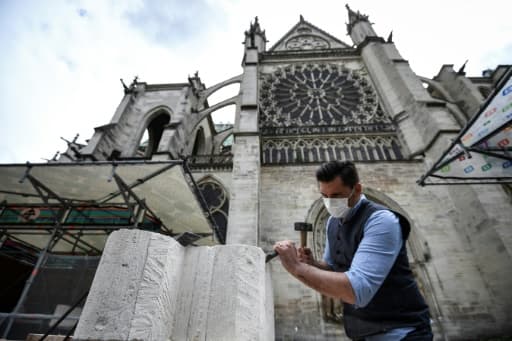 Un tailleur de pierre explique ses gestes à des visiteurs devant la basilique Saint-Denis, le 5 juin 2020 Un tailleur de pierre explique ses gestes à des visiteurs devant la basilique Saint-Denis, le 5 juin 2020