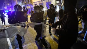 Des membres de la police régionale catalane Mossos d'Esquadra prennent une banderole sur un manifestant à la suite d'une manifestation contre l'emprisonnement du rappeur espagnol Pablo Hasel à Barcelone le 21 février 2021. 