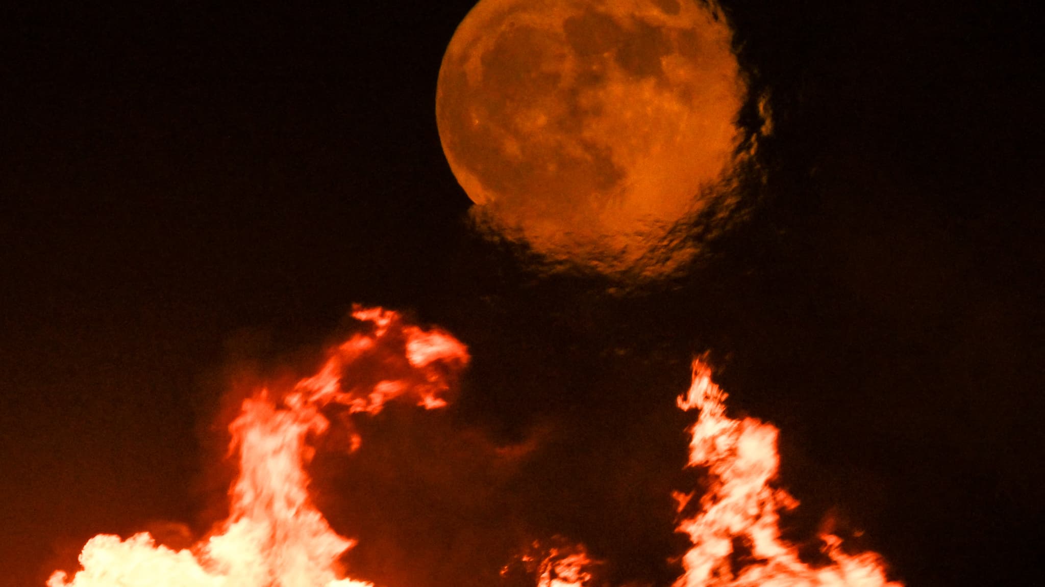 Une super lune bleue se lève sur les torchères d'un champ pétrolier près de la ville portuaire de Basra, dans le sud du pays, le 19 août 2024.