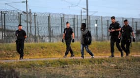 Des policiers suivent un migrant à Coquelles, près de Calais