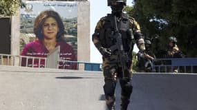 Un officier de sécurité palestinien monte la garde devant une bannière montrant la journaliste palestino-américaine Shireen Abu Akleh tuée par balles en Cisjordanie, le 15 juillet 2022