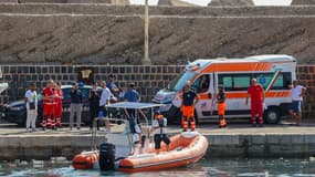 Des carabiniers italiens se tiennent sur le quai et des secours après le naufrage d'un voilier au large de la côte de Porticello, au nord-ouest de l'île de Sicile, le 19 août 2024.