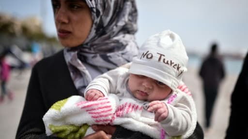 Dans les bras de sa mère migrante, un bébé porte un bonnet où il est écrit "No Turkey" Dans les bras de sa mère migrante, un bébé porte un bonnet où il est écrit "No Turkey"