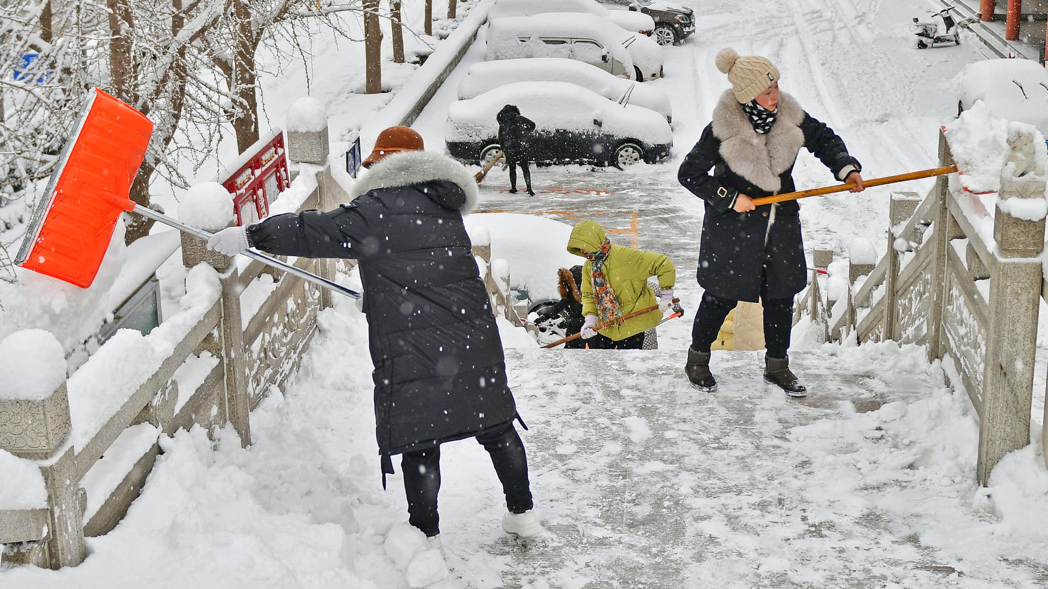 Des habitants de Yantai, dans la province chinoise du Shandong, déneignent les trottoirs, le 20 décembre 2023.