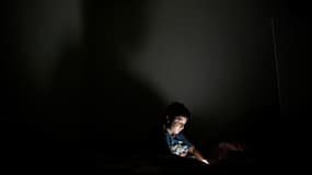 Un enfant joue sur un smartphone dans sa chambre à San Salvador en octobre 2018