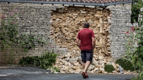Un habitant passe devant le mur endommagé d'une maison dans le village de La Laigne, en Charente Maritime, le 17 juin 2023, au lendemain d'un fort séisme.