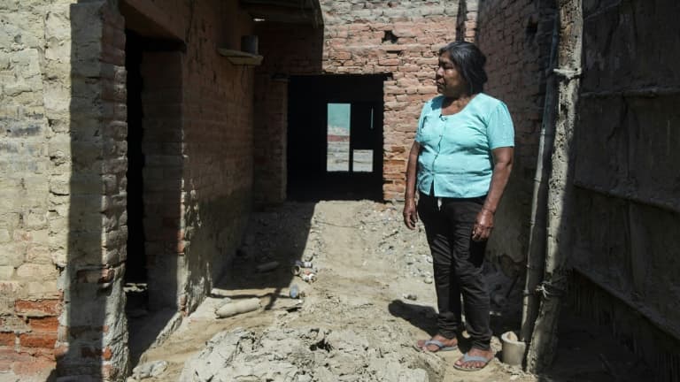 Une femme devant sa maison endommagée par les inondations provoquées par le phénomène climatique El Nino, le 17 octobre 2021 à Piura, dans le nord du Pérou