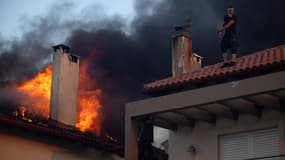 Des habitants tentent d'éteindre l'incendie d'une maison en feu lors d'un incendie de forêt à Kryoneri, près d'Athènes, le 26 juillet 2025.