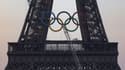 Des équipes finissent d'accrocher les anneaux olympiques à la tour Eiffel, le 7 juin 2024, à Paris