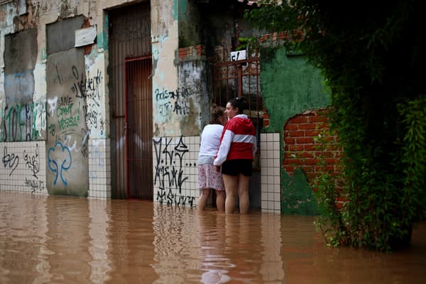Des habitants du quartier de São Geraldo se tiennent devant leur maison dans une rue inondée à Porto Alegre, dans l'État du Rio Grande do Sul, au Brésil, le 4 mai 2024.
