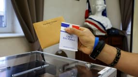 Un électeur tient une carte électorale et un bulletin de vote avant de voter dans un bureau de vote à Etaples, pour le second tour des élections régionales, le 27 juin 2021