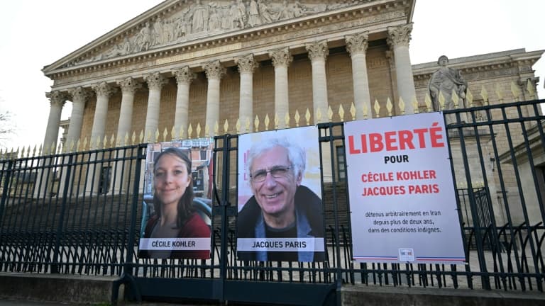 Les portraits de Cécile Kohler (G) et de Jacques Paris (C) exposés sur les grilles du Palais Bourbon, siège de l'Assemblée nationale française à Paris, le 25 mars 2025