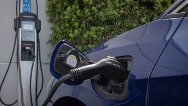 Une voiture électrique branchée sur une bore de recharge.