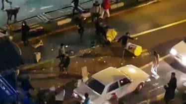 Image extraite d'une vidéo fournie par l'agence iranienne Mehr News montrant un groupe d'hommes tapant dans des plots de circulation dans une rue de Téhéran le 30 décembre 2017