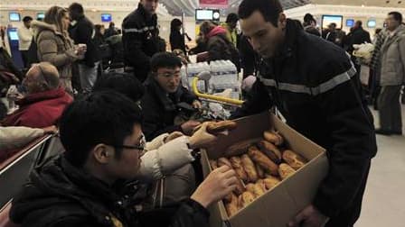Distribution de vivres à Roissy, où 700 voyageurs devront passer le réveillon de Noël en raison des mauvaises conditions météorologiques qui ont désorganisé le transport aérien. /Photo prise le 24 décembre 2010/REUTERS/Julien Muguet