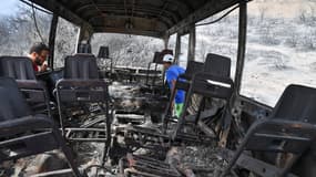 Des Algériens contrôlent un bus calciné dans lequel au moins 12 personnes auraient été brûlées à la suite d'incendies dans la ville algérienne d'El-Kala, le 18 août 2022.