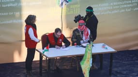 Des membres de la Croix-Rouge signent des documents sur un bureau installé par le Hamas à Jabalya, avant la libération de l'otage Agam Berger, à Gaza le 30 janvier 2025