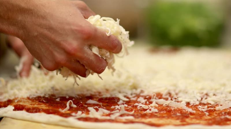 Un homme met du fromage sur une pizza dans le meilleur restaurant de pizza de Miami, en Floride

