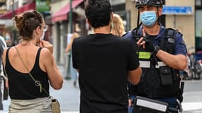 Un policier masqué demandant à des passants de porter un masque à Paris, rue Montorgueil
