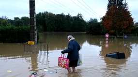 Une personne sinistrée porte ses courses les pieds dans l'eau à Pommeuse, en Seine-et-Marne, le 10 octobre 2024