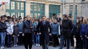 Nicolas Sarkozy (au centre), entouré du ministre de l'Education nationale Luc Chatel (à droite) et de la directrice du collège François Couperin, à Paris, après une minute de silence pour rendre hommage aux victimes de la tuerie de Toulouse, qui ajoutée à