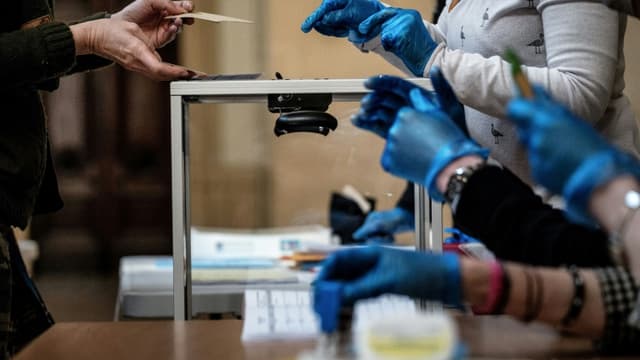 Un électeur s'apprête à placer son bulletin dans l'urne, le 15 mars 2020 à Lyon, lors du premier tour des municipales