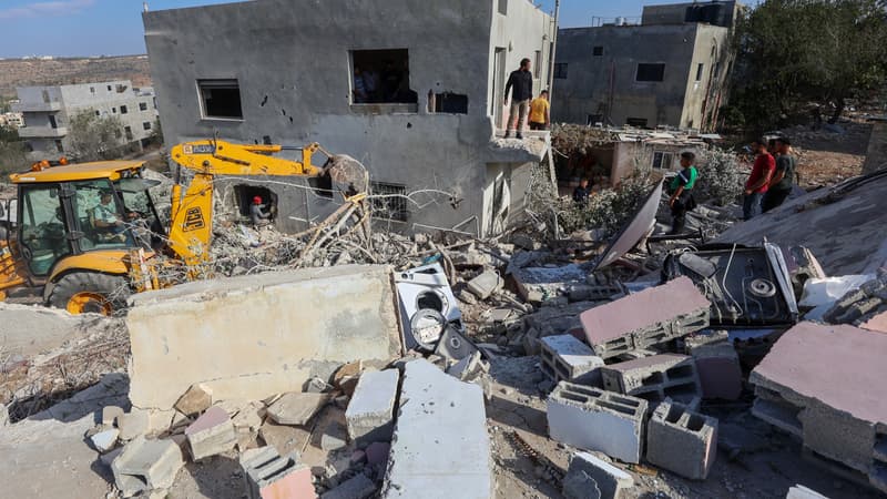 Des Palestiniens regardent une pelleteuse déblayer les décombres de la maison du chef adjoint du bureau politique du Hamas, Saleh al-Arouri, après sa démolition par les forces israéliennes dans le village d'Aroura, en Cisjordanie occupée, le 31 octobre 2023, dans le cadre des batailles entre Israël et le mouvement palestinien du Hamas.