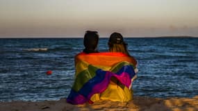 Deux femmes assises sur une plage avec un drapeau LGBT sur les épaules en novembre 2021 (Photo d'illustration).