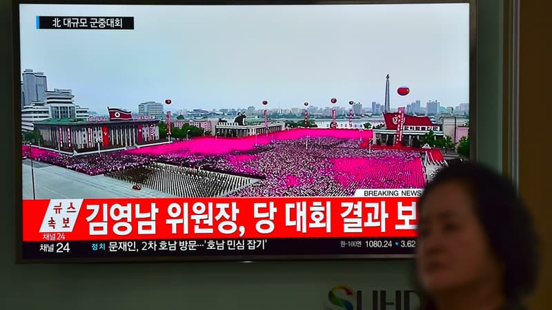 Une femme passe devant un écran diffusant des images de la parade donnée à Pyongyang en l'honneur de Kim Jong-Un.