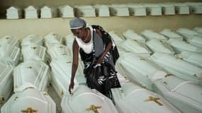 Une survivante du génocide rwandais de 1994 ouvre les cercueils contenant les restes des victimes au Mémorial du génocide de Nyanza avant un enterrement de masse à Kigali le 2 mai 2019.