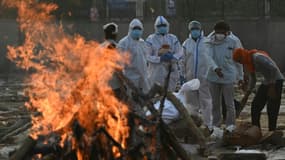 Des proches vêtus d'équipements de protection rendent hommage à une victime du Covid-19 incinérée à New Delhi en Inde le 11 mai 2021