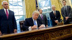 Le président américain Donald Trump signe des décrets entouré de son vice-président Mike Pence, le 23 janvier 2017, dans le Bureau ovale de la Maison Blanche