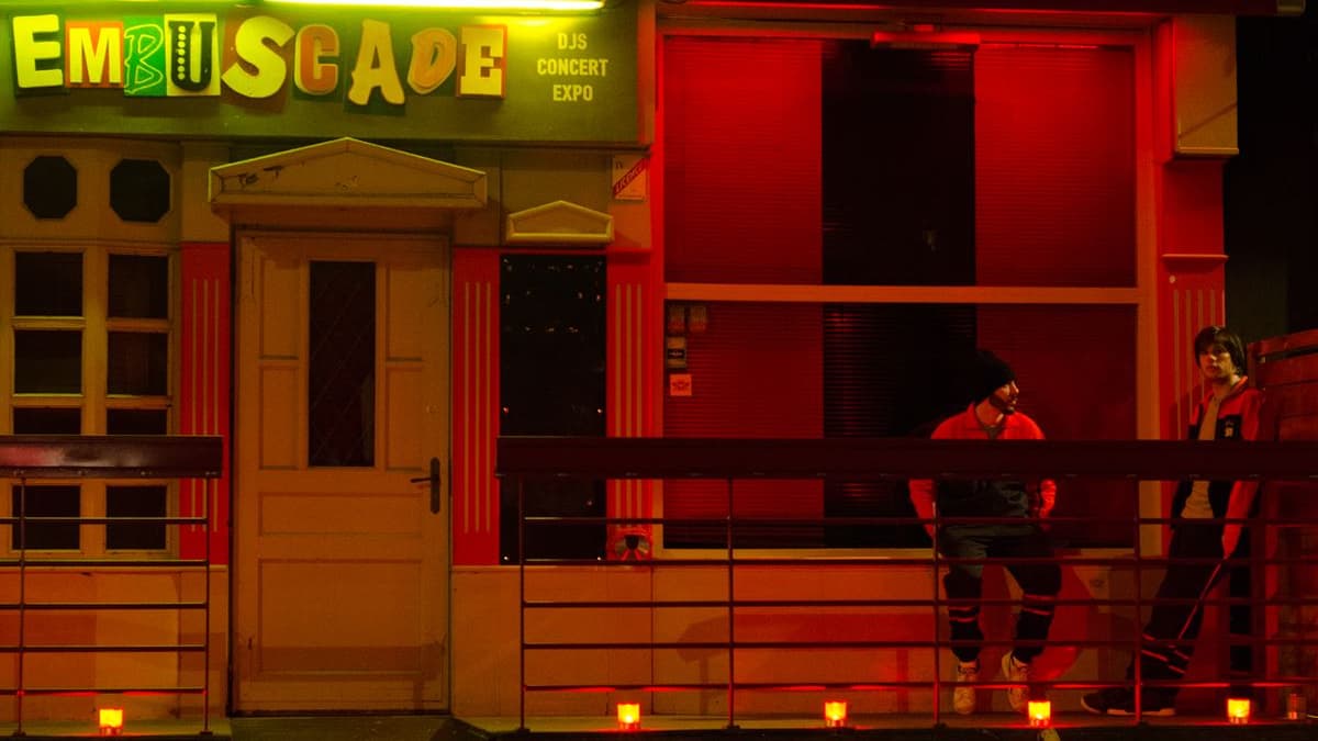 Orelsan et Gringe devant la façade du bar l'Embuscade dans le film Comment c'est loin