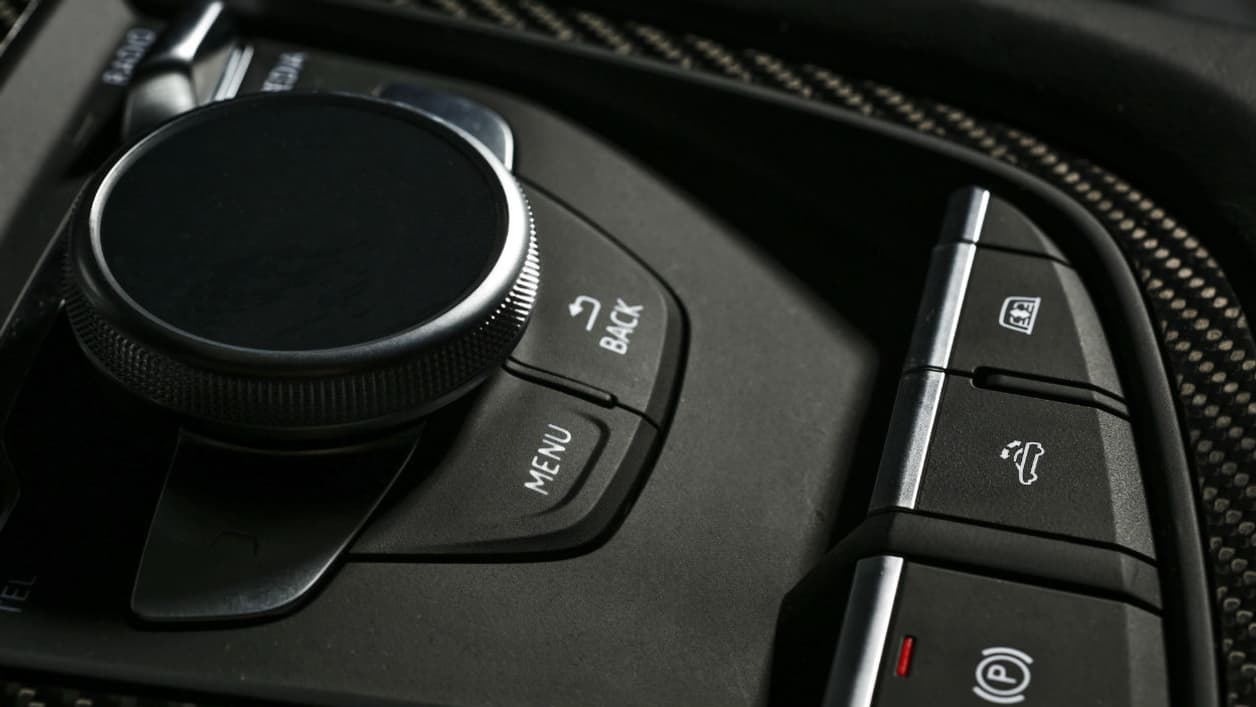 A droite du bouton de rangement/ouverture du toit, celui pour abaisser la vitre séparant l'habitacle du compartiment moteur A droite du bouton de rangement/ouverture du toit, celui pour abaisser la vitre séparant l'habitacle du compartiment moteur