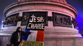 Une femme tient un bougie près d'une affiche "je suis Charlie", lors de la commémoration des deux ans après les attaques de 2015 qui avaient fai 17  victimes, le 7 janvier 2017 à Paris