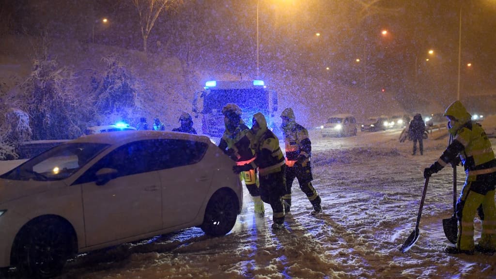 Des pompiers poussant un véhicule enneigé à Madrid, le 8 janvier 2021 Des pompiers poussant un véhicule enneigé à Madrid, le 8 janvier 2021