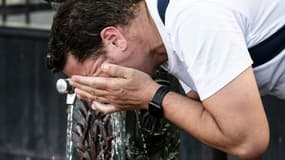 Un homme se rafraîchit le visage à une fontaine dans une rue de Paris en pleine canicule, le 13 juillet 2022