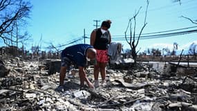 Des habitants de Lahaina, à Hawaï, au milieu des ruines de leur maison brûlée lors des incendies, le 13 août 2023