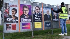 Un employé colle des affiches de campagne sur des panneaux électoraux à Saint-Herblain, près de Nantes, le 28 mars 2022
