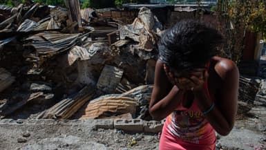 Une femme en larmes devant sa maison après que des bandes armées l’ont incendiée, à Port-au-Prince, le 17 décembre 2024.