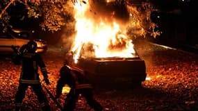 Pompiers tentant de contrôler l'incendie d'une voiture à Clichy-sous-Bois, fin octobre 2005. Le parquet de Bobigny (Seine-Saint-Denis) a requis un non-lieu pour deux policiers poursuivis pour la mort accidentelle par électrocution de deux adolescents, aff