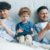 Des parents et leur enfant utilisant des smartphones. 
